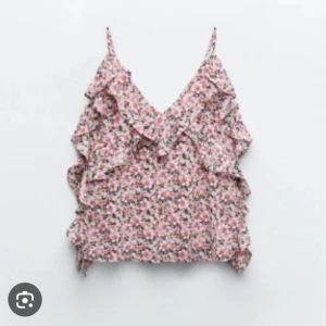 Blommig volanglinne från Zara - Supersöt blommig linnetopp från Zara med volangdetaljer och tunna axelband. Mönstret är småblommigt i rosa, lila och beige toner. Luftig och flowy passform, perfekt för varma dagar. Materialet känns lätt och svalt mot huden.