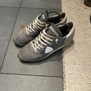  Philippe Model sneakers  - Snygga sneakers från Philippe Model i grå toner med detaljer i mocka och textil. Skorna har snörning, rund tå och platt sula. Stilren design med logotyp på sidan och bekväm innersula i skinn. Perfekta för dig som gillar en clean och urban look. Strl 41 passar även 42