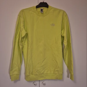 Ljusgrön/gul sweatshirt från The North Face - Säljer en ljusgrön/gul (svårt att fånga färgen på bild) sweatshirt från The North Face med broderad logga på bröstet och ryggen. Tröjan har rund halsringning, ribbade muddar och är unisex. Inte mycket använd men har tyvärr fått fläckar som ej går bort. 