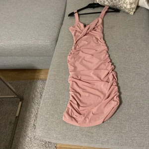 Rosa omlottklänning från SHEIN - Supersnygg rosa långklänning från SHEIN i storlek S. Klänningen har omlottdesign upptill, breda axelband och draperade detaljer längs sidorna. Materialet är ribbat och stretchigt, vilket ger en tight och smickrande passform.oanvänd eller använd 1 gång. Helt ny.