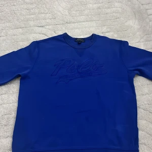 Polo Ralph Lauren tröja. - Polo Ralph Lauren tröja – blå Snygg och stilren sweatshirt från Polo Ralph Lauren i en klarblå färg. Tröjan har ett ton-i-ton broderi med texten Polo på bröstet. Klassisk modell med rund hals och normal passform. Materialet är mjukt och bekvämt, perfekt för vardagsbruk eller en avslappnad look.