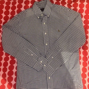 Blårutig skjorta från Polo Ralph Lauren - Köp denna för endast 249! (Nypris 1600) Säljer en blårutig skjorta från Polo Ralph Lauren i slim fit. Skjortan har klassisk krage, knappar framtill och broderad logga på bröstet. Tillverkad i bomull och har långa ärmar. Perfekt för dig som gillar stilrena och tidlösa plagg.