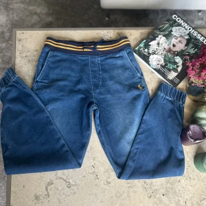 Blå jogger-jeans från Polo Ralph Lauren - Snygga blå jogger-jeans från Polo Ralph Lauren med resår och snörning i midjan samt gula ränder. Mjukt jeansmaterial, elastiska benslut och klassisk broderad logga på ena fickan. Perfekta för en chill och sportig look.