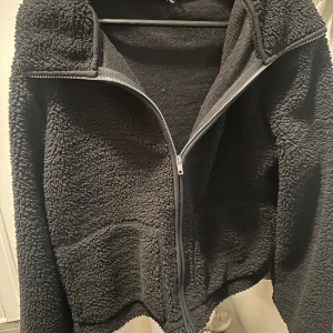 Svart teddyjacka  - Mysig svart teddyjacka med hel dragkedja framtill och hög krage. Jackan har en fluffig, fleece-liknande yta och två stora fickor framtill. Aldrig använd mer än testat, storlek M💕