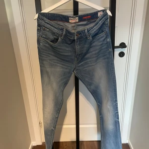 Crocker Skinny Jeans 33/34 ljusblå - Ljusblå skinny jeans från Crocker med klassisk femficksdesign och orange sömmar. Modellen är 302 Skinny Fit och har en smal passform hela vägen ner. Jeansen är tillverkade i mjukt denimtyg för extra komfort och har snygga slitningar framtill.