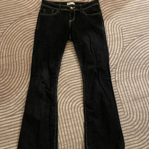 Bootcut jeans från Perfect Jeans, svart - Svarta bootcut jeans från Perfect Jeans med kontrasterande vita sömmar och klassisk femficksdesign. Jeansen har låg midja, knappt använda och säljer för att de ej passar