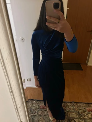 Mörkblå  lång klänning  med slits - Mörkblå lång klänning, knappt använd Köpt utomlands då den var costumized. Har en slit upp till knät vid vänster ben. Mjuk material. Passar perfekt för mig som har stl S men passar  också jätte fint för de som har stl Xs samt M. Köpt för 1000kr.