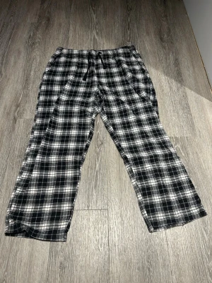 Flanellbyxor strl. XL - Rutiga flanellbyxor i svart och vitt med dragsko i midjan. Byxorna har en avslappnad passform och är perfekta för chill dagar hemma.