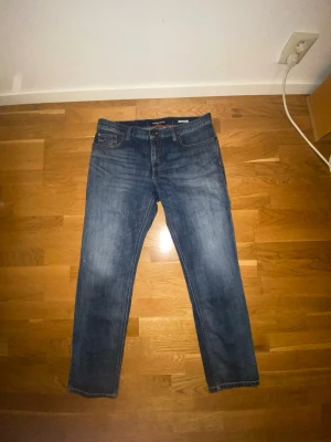 Blå jeans från Alberto W36/L30 - Säljer ett par klassiska blå jeans från Alberto med snygg tvätt och raka ben. Jeansen har fem fickor, normal passform och subtila slitningar för en avslappnad look. Perfekta för dig som gillar stilrena och bekväma jeans.