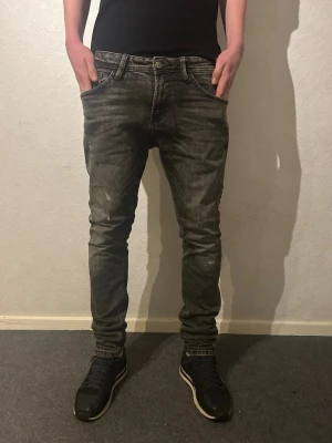 Grå slim jeans Tom Tailor - Säljer ett par gråa slim fit jeans från Tom Tailor, modell Piers Slim. Jeansen har en snygg tvättad look, klassiska fem fickor och bälteshällor. Materialet är jeans och passformen är smal längs benen. 