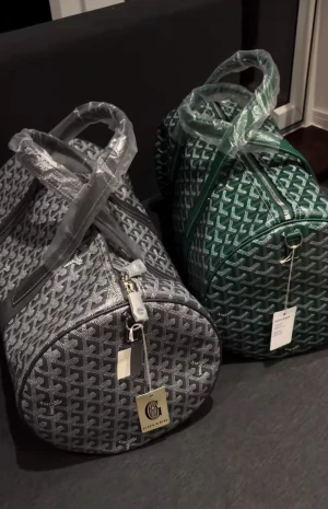  weekendväskor i silver och grönt - Två snygga weekendväskor från , en i silver och en i mörkgrönt. Väskorna har det klassiska -mönstret, rundad form och dragkedja upptill. Perfekt storlek för resor och med rejäla handtag. Märkets logga syns tydligt på båda väskorna. Kan skicka 7-18 mer bilder privat 
