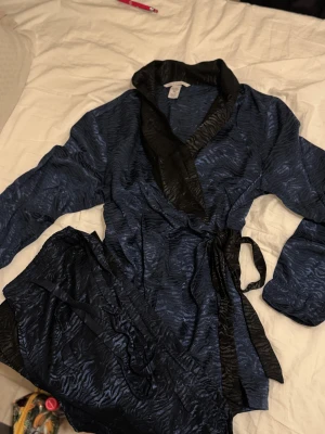 Blå omlottväst Victoria's Secret - Snygg omlottväst från Victoria's Secret i mörkblått med svart zebramönster. Västen har bred svart krage och knytband i midjan. Byxorn har storlek M🤍