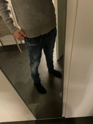 Replay New Luz blå jeans, storlek 25 - Säljer ett par Replay New Luz jeans i klassisk blå tvätt med snygga slitningar och detaljer på bakfickorna. Jeansen har en slim passform och sitter tajt längs benen. Perfekta för dig som gillar en modern och stilren look. Materialet är mjukt och följsamt jeans. De är avklippta så skulle nog säga att längden är L28-30. Jah på bild är 152cm och det skulle kunna passa upp till 160 och lite längre.
