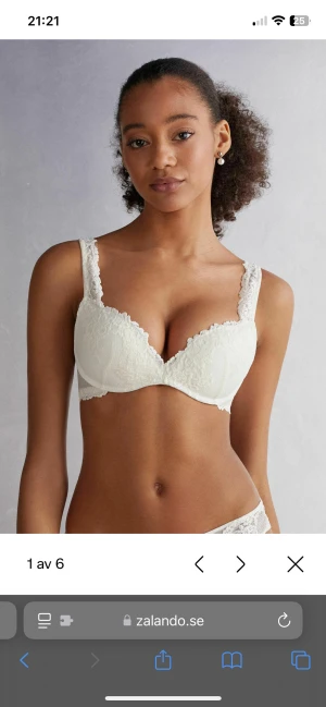 Vit spetsbh med tunna axelband - Supersöt vit bh med tunna axelband och spetsdetaljer längs kanterna. Blusen har en feminin v-ringning och broderade blommor framtill. Baksidan är enkel med justerbara band och spetskant. Perfekt för dig som gillar romantisk och stilren look.