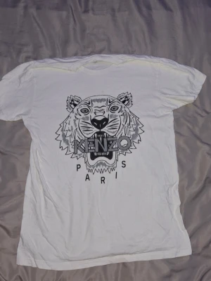 Vit t-shirt med tryck - Säljer en vit t-shirt med stort cleant tryck och texten 'Kenzo Paris' på framsidan. Perfekt för dig som gillar streetstyle och vill sticka ut med en exklusiv tröja