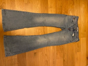 Blå bootcut jeans  - Snygga ljusblå bootcut jeans  med röda kontrastsömmar på bakfickorna och längs midjan. Klassisk femficksmodell med normal passform och lätt slitning på framsidan. Perfekt för dig som gillar retrovibbar och breda ben. De är ifrån Lois men plick låter mig inte lägga till de märket 