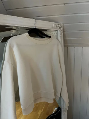 Vit loose sweatshirt i bomull - En stilren vit sweatshirt med rund hals och långa ärmar. Tröjan har en loose passform och är tillverkad i mjuk bomull, perfekt för chill dagar. Ribbad kant vid hals, ärmslut och nederkant ger en clean look.