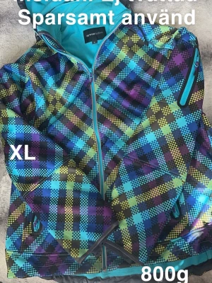 Rutig softshelljacka från mywearactive XL - Färgstark vindjacka med rutigt mönster i blått, lila, gult och svart. Jackan har dragkedja framtill, fickor med dragkedja och en cool sportig vibe. Perfekt för dig som gillar att sticka ut och vill ha en jacka som är både snygg och funktionell.🌸 Sparsamt använd. Något mörkare på insidan. Fleece på insidan. Ej tvättad. Storlek XL