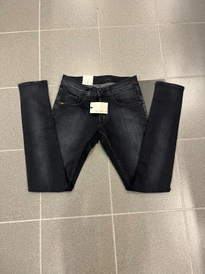 Svarta slimmade jeans från Tiger of sweden W30 L34 - Snygga svarta jeans från T/J med smal passform och smala ben. Klassisk femficksdesign, svarta sömmar och diskret tvättad look. Perfekt för dig som gillar en modern och stilren vibe. Materialet är stretchigt jeans för extra komfort.