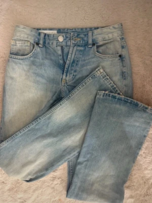 Ljusblå raka jeans från Zara - Säljer ett par ljusblå jeans från Zara med klassisk femficksmodell och raka ben. Jeansen har hög midja och är tillverkade i bomull med snygg tvättad look. Perfekta för en avslappnad och trendig stil.