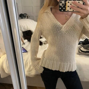 Beige stickad tröja från Oui Moments - Säljer en beige stickad tröja från Oui Moments med v-ringad krage och breda muddar. Tröjan har långärmade ärmar och är gjord i ett grovt stickat material som ger en chill och avslappnad vibe. Perfekt att styla med jeans eller kjol.         60 % bomull 40 % polyakryl (akryl) Alltså en blandning av bomull och syntetiskt akrylmaterial.
