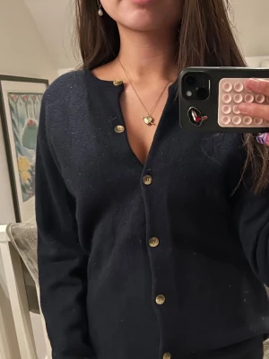 Mörkblå kofta med guldfärgade knappar - Säljer en stilren mörkblå kofta med guldfärgade knappar framtill. Koftan har långärmad design och en klassisk rund halsringning. Skulle säga att det passar stl s/m