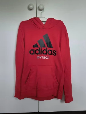 Adidas x Gosha Rubchinskiy hoodie - Röd hoodie från Adidas i samarbete med Gosha Rubchinskiy. Mycket gott skick, inga sprickor i trycket. 100% Cotton.  Finns en gömd ficka inuti med zipper.  Har du några frågor så tveka inte att skicka iväg ett meddelande.