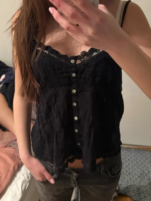 Svart spetsdetaljerad linnetopp - INTRESSEKOLL PÅ DEN KÄNDA ZARA LINNET SOM INTE FINNS LÄNGRE Säljer en svart linnetopp med spetsdetaljer längs urringningen och nederkanten. Toppen har knappar framtill och tunna axelband. Materialet är lätt och luftigt, perfekt för varma dagar eller lager på lager. Supersnygg till både jeans och kjol!