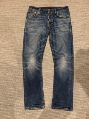 Nudie Jeans W33 - Grim Tim - Tja jag säljer ett par snygga blå Nudie Jeans i modellen Grim Tim med storleken 33/32. Dem är unika och har snygga fades. Hör av dig vid frågor👍 kan gå ner i pris vid snabb affär