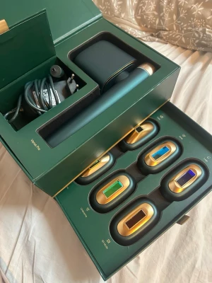 JOVS Venus Pro IPL hårborttagningsapparat - Säljer en JOVS Venus Pro IPL hårborttagningsapparat i mörkgrönt och guld med sex olika utbytbara huvuden för ansikte, armar, ben, bikinilinje, armhålor och SR-läge. Kommer med laddare och förvaringsbox. Snygg och modern design, perfekt för hemmabruk.