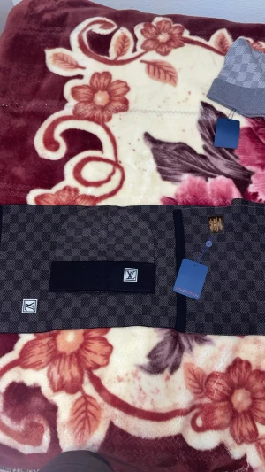 Rutig väst från Louis Vuitton - Säljer en snygg väst från Louis Vuitton i mörkgrått och svart med klassiskt rutigt mönster. Västen har LV-logga framtill och svarta detaljer längs kanterna. Materialet känns mjukt och exklusivt, perfekt för dig som gillar stilrena plagg med lyxig känsla.