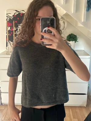 Mörkgrå stickad kortärmad tröja - Mysig mörkgrå stickad tröja med korta ärmar och rund halsringning. Den är ifrån Gina Tricot Young i storlek 158/164 men är som en Xs. Tröjan har en rak, lite boxig passform och är perfekt till allt. 