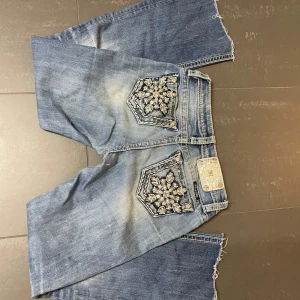 Miss me jeans  - Snygga jeansshorts från Miss Me med unika broderade fickor och fransiga kanter. Perfekta för en avslappnad stil med en touch av detaljer. De har en klassisk blå jeansfärg och är tillverkade i ett slitstarkt material. Klippta längst ner. Innerbenslängden är runt 66cm och midjemåttet är 36 🤗 frågor tas dm!