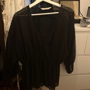 Svart prickig blus - Svart blus diskret prickigt mönster i tyget från ZARA. V-ringad hals, markerad midja och trekvartsärmar i transparent material. Tunnt linne med spetsdetalj under. 