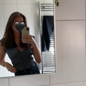 Svart prickig blus med volang - Svart blus med vita prickar och volangdetaljer vid ärmslut och midja. Blusen har v-ringad hals och korta ärmar med lätt rynk, från ZARA!