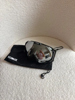 Bliz Carver svarta skidglasögon - Säljer ett par Bliz Carver skidglasögon med spegelglas och svart ram. Glasögonen har en bred, justerbar svart och vit rem med Bliz-logga. Snygg och sportig design. Litet skrapmärke som knappt syns men de syns på en av bilderna. Använda en gång. 