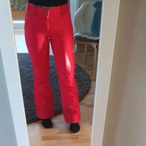 Rosa termobyxor Peak Performance XS - Snygga röda täckbyxor från Peak Performance i storlek XS. Byxorna har en klassisk bootcut-passform och är tillverkade i slitstarkt syntetmaterial. Perfekta för vintern och har broderad logga på benet. Sitter skönt i midjan och har knappstängning.