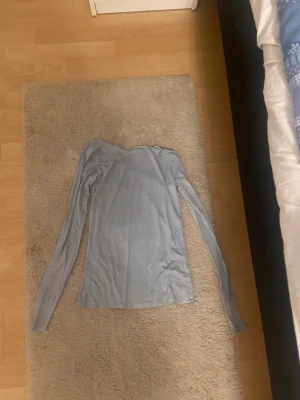 Ljusgrå långärmad tröja Stories - Superskön ljusgrå långärmad tröja från Stories i storlek S. Tröjan har en enkel och clean design med rund hals och smal passform. Perfekt att styla med jeans eller under en jacka. Materialet känns mjukt och lätt mot huden.