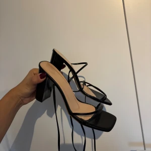 Svarta klackar med snörning - Säljer ett par svarta klackar med fyrkantig tå, hög klack och tunna remmar som snörs runt ankeln. Storlek 38 men minns tyvärr inte vart de är köpta🌸