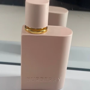 Burberry parfym i rosa flaska - Stilren Burberry parfym i matt rosa flaska med gulddetalj. Perfekt för dig som gillar minimalistisk design och vill ha något som sticker ut på hyllan.