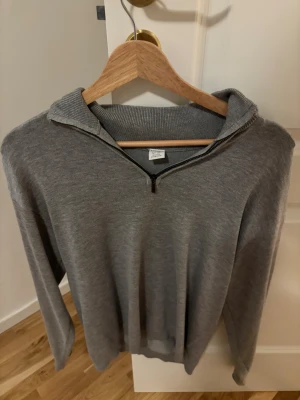 Grå half zip tröja från Lindex - Snygg grå långärmad tröja från Lindex med ribbad krage och half zip-dragkedja framtill. Tröjan är i mjukt material och har en clean, enkel look som funkar till många stilar. Perfekt för dig som gillar basic men ändå vill ha något med lite edge.