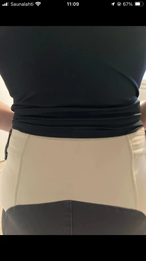 Svart-beige ridbyxor Helix strl S - Snygga ridbyxor från Helix i storlek S, med svart och beige färgblock. Byxorna har hög midja, bälteshällor, dubbla knappar och dragkedjor vid fickorna. Materialet är en mix av polyester, bomull och elastan för extra stretch och komfort.