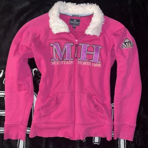 Rosa zipup tröja - Rosa tröja från mountain horse med fluff vid kragen. Strl 170 junior men sitter som en XS. Även insydd vid midjan för att sitta lite tightare där. Har några små skavanker men är i allmänt bra skick!