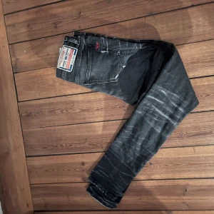Diesel D-Strukt svarta jeans, stl 29/32 - Säljer ett par svarta Diesel D-Strukt jeans med snygga slitningar och tvättade detaljer. Modellen har smal passform och raka ben.