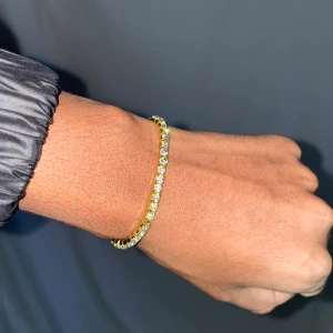 Tennischain armband  - Snygg guldfärgad tenniskedja som passar perfekt till både vardag och fest! Glittrande stenar som fångar ljuset på ett riktigt snyggt sätt. Prisvärd accessoar för bara 99kr 
