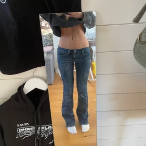 Blå bootcut jeans från Gina Tricot - Snygga blå jeans från Gina Tricot med bootcut passform och låg midja. Jeansen har ett hål i sömmen längst upp men syns inte när man har de på sig. Se sista bilderna.