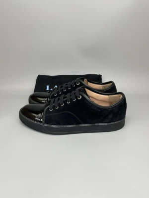 Lanvin Dbb1 Patent Cap Toe Sneaker Svart - • The shoes have been gently used and are in really good condition  • Size: EU45 / UK11 (fits 45.5-46)  • Color: Black  • Retail price: 5000 SEK / 450€  • Dustbag is included
