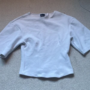 Vit topp med  större ärmar från Gina Tricot - Säljer en stilren vit topp från Gina Tricot i storlek XS. Toppen har rund halsringning och större vid ärmarna med en något figurnära passform. Materialet är mjuk bomull som känns skönt mot huden. Perfekt för dig som gillar enkla och cleana looks.