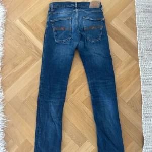 Nudie Grim Tim - Nudie jeans i bra skick i modell Grim Tim och färgen Indigo Blue. De har lagats i nudie butiken för ett mindre hål. Storlek 30/32.