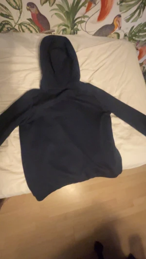 Marinblå Sail Racing hoodie - Snygg marinblå hoodie från Sail Racing med vit logga tryckt på bröstet och en liten logga på huvan. Tröjan har stor känguruficka framtill och är tillverkad i mjuk bomullsmix. Perfekt för chill eller när du vill ha en clean look. Priset kan diskuteras